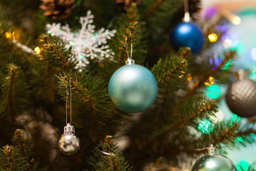 Beautiful green Christmas tree decorated with blue balls and garlands. Close-up photo. Sparkling background