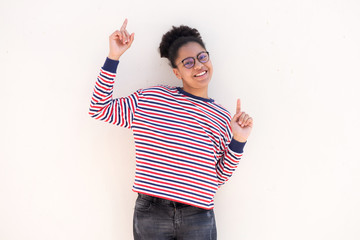happy young girl with glasses pointing fingers up against white background