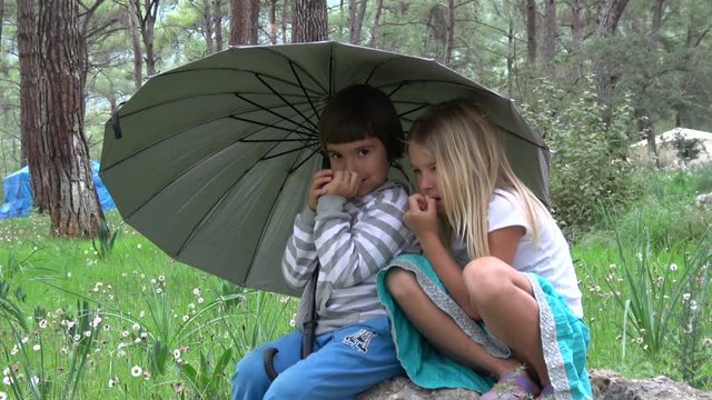 Akyaka, Mugla, Turkey - 10th of November 2019: 4K Girl and boy under an umbrella pick their noses