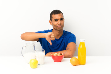 Young man having breakfast in a table showing thumb down sign