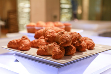 Stack of croissants in a hotel breakfast buffet on a white plate