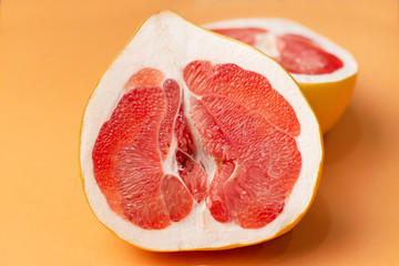 Fresh grapefruit on an orange background, close-up. Sex concept. The concept of women's health