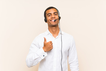 Young brunette man working with a headset with thumbs up because something good has happened