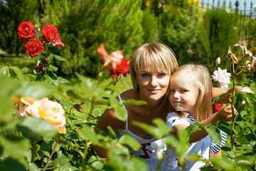 young pretty woman with cute daughter in rose garden at summer happy smiling, lifestyle people concept