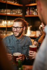 Group of friends drinking beer, chatting and having good time at pub. Night out.