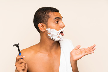 Young handsome man shaving his beard over isolated background with surprise facial expression