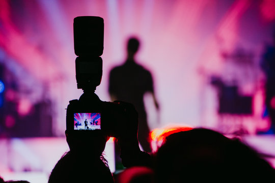 A professional reflex camera with a flash taking photos to a musician in a concert. Live Music. Festival. Horizontal