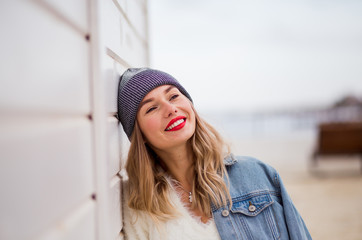 Urban style blond woman wearing hat and jeans jacket with red lips and beautiful smile. Space for text.