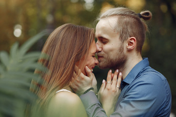 Cute couple in a park. Lady in a white dress. Man in a blue shirt