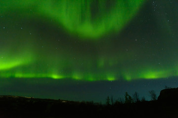 Fototapeta na wymiar Aurora borealis over the hills. At night in the sky in the north.