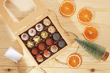 Christmas candy gift box on the wood background with dried oranges and christmas tree. Top view.