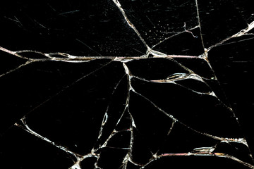 Realistic cracked glass texture on black background. The effect of broken glass. Harvesting. Close up.
