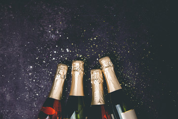 Bottles of champagne with gold glitter and space for text on dark background © Natalia Klenova