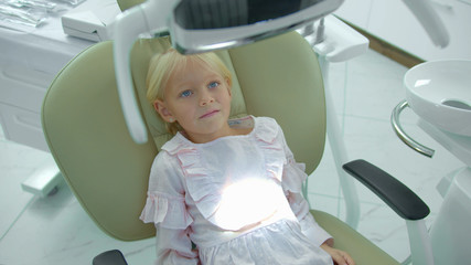 Girl sits in dental chair, turn off and on the lamp