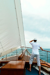 Stylish, young man on deck of a cruise ship, looking into the distance against the blue sky. Concept of sea travel and recreation