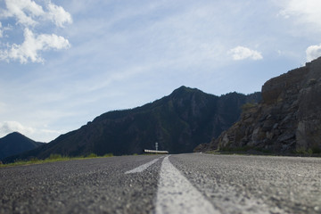 Asphalt road with a dividing strip shot close-up. The road leading to the mountains. Altai