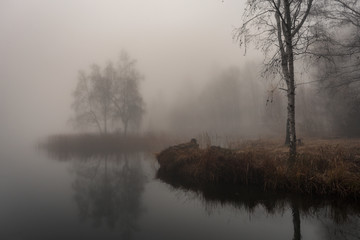Autumn landscape with deep mist on the lake 