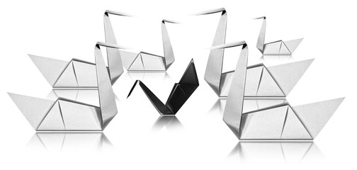 Bullying concept - Six white paper swans face a black swan © Alberto Masnovo