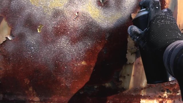 Homeless man spray painting old train wagon with aerosol can