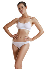 Fototapeta premium Young woman in white underwear, with bundled hair, hands on hips, posing isolated on white. Plastic surgery, aesthetic cosmetology. Close-up shot.