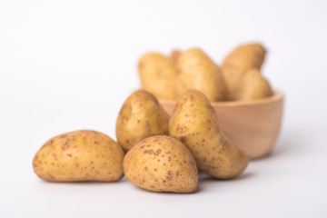 Close up of organic raw potato in a brown wooden bowl on a white background