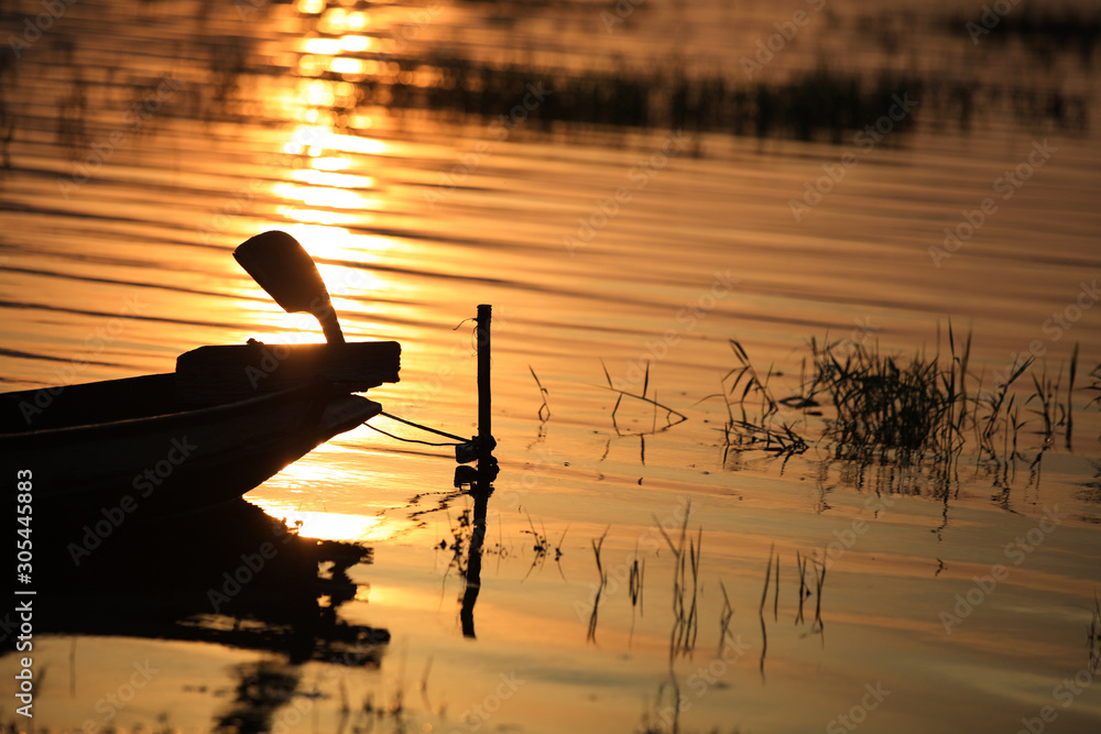 Wall mural silhouette close up end of fisherman boat with sunset reflection on water