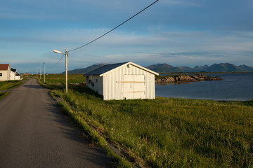 Fototapeta na wymiar Rorbu house. Fishing hut in beautiful nature landscape. Amazing scenic outdoors view. Ocean and mountains. Dramatic clouds. Tourist landmark. Travel and adventure lifestyle. Explore North Norway