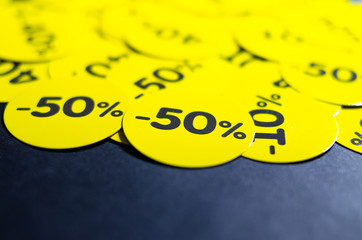 Yellow round stickers with discounts of 10 to 50 percent. Sell-out. Discounts on a black background. Black Friday. Price fall. Posters. Macro discounts.