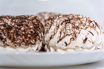 Marshmallows with chocolate on a white background close-up. Sweet, gentle dessert.