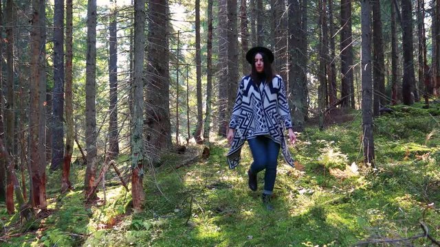 Girl walks in the autumn forest. yellow leaves. A blogger travels and we create new content. Sun rays. Authentic poncho and black hat. Ukrainian Carpathian Mountains.