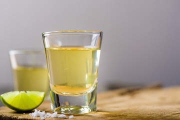 Tequila in a shot glass on a brown wooden background prepared for a party