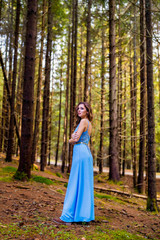 Obraz na płótnie Canvas Beautiful woman in blue dress in the forest in autumn day