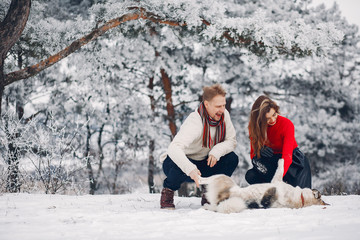 Cute couple in a winter park. Woman palying with a dog. Lady in a red sweater