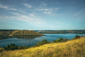 Fototapeta na wymiar nature reserve landscape background photography of hill land and lake summer time scenic view with fuzzy cloudy sky 