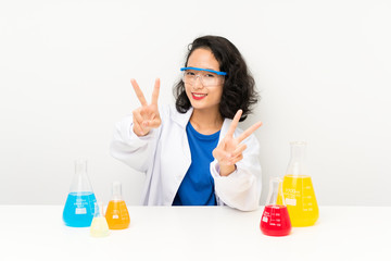 Young scientific asian girl smiling and showing victory sign