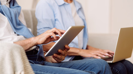 Modern senior couple using gadgets, closeup, crop