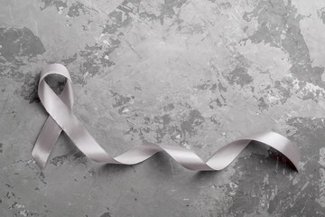 grey ribbon on concrete background. Parkinson's disease or brain cancer awareness concept