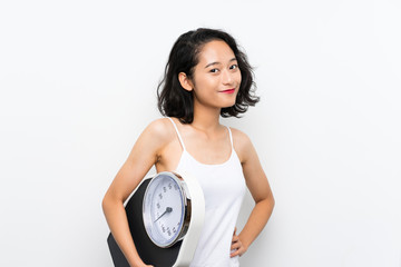 Young asian girl with weighing machine over isolated white background