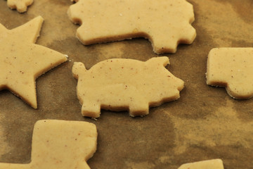 Raw dough for Christmas cookies and cookie cutters shaped glove, Christmas star, snowman, pig, gingerbread man. Concept of winter holidays and work together. Baby Jesus or Santa claus coming soon