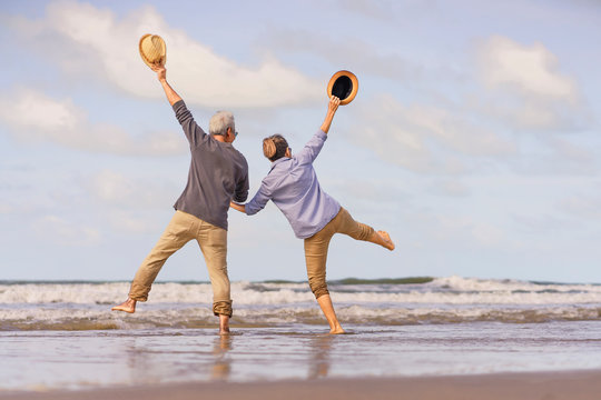Asian senior couple jumping on the beach.elderly honeymoon together very happiness after retirement.plan life insurance.Activity after retirement on summertime