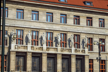 Sculptures of naked people over the entrance to the building with a shadow on the wall