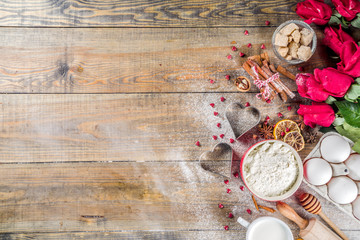 Valentine day baking background. Ingredients for cooking Valentine's heart cookies. Flour, eggs, sugar, spices on wooden background with red flower roses. Top view copy space.