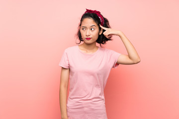 Asian young woman over isolated pink background making the gesture of madness putting finger on the...