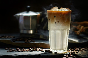 Still life of Ice milk coffee with smoke on black stone  table, shooting in studio. Low key toned image. Free space for text. Good drink for healthy ideas concept for advertising. Selective focus.