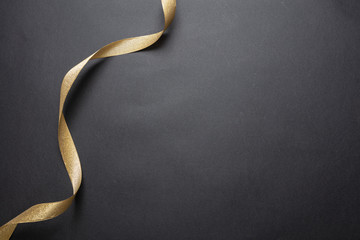 Golden ribbon curl on black color background. Minimal card template