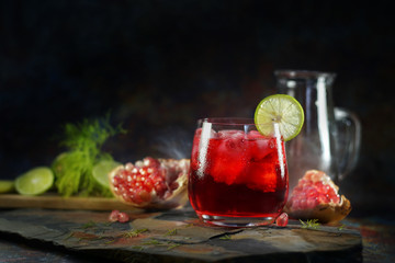 Still life photography of Pomegranate juice lemon soda with pomegranates seeds on table. Shooting at studio,low key toned image, Selective focus and free space for text. Healthy fruits drink concept.