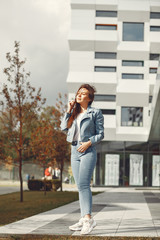 Beautiful girl in a city. Stylish girl near gray building