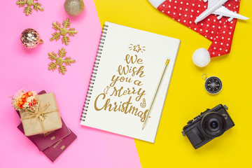 Fototapeta na wymiar Christmas travel concept. White airplane, passport, camera and christmas ornaments decoration on pink yellow background. Merry Xmas and happy New Year celebration.