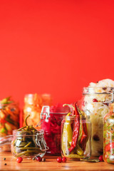 Assortment of various fermented and marinated food over wooden background, copy space. Fermented vegetables, sauerkraut, pepper, garlic, beetroot, korean carrot, cucumber kimchi in glass jars.