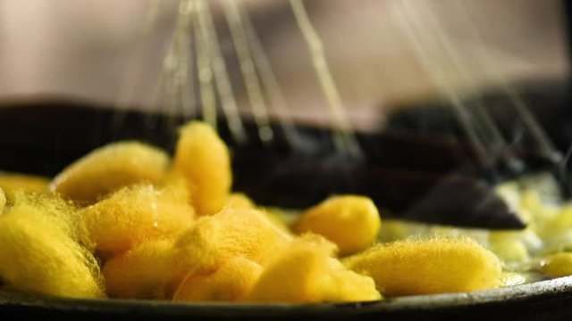 The process of producing yellow silk by hand closeup from Cocoon to Silk thread, Thailand. Processing Boiling silkworm cocoons in hot water.Traditional silk production on the Thai countryside.